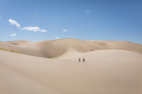 High angle view of hikers walking on desert at Great Sand Dunes National Park during sunny day stock photo