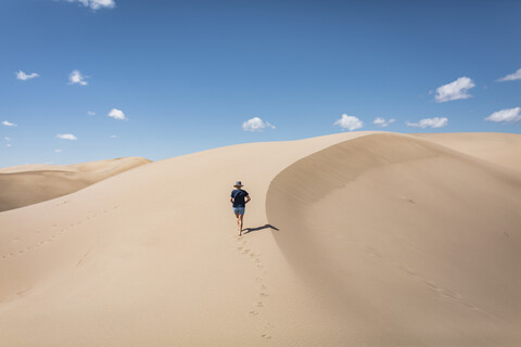 Hohe Winkel Ansicht der Frau zu Fuß auf Sand in Great Sand Dunes National Park während sonnigen Tag, lizenzfreies Stockfoto