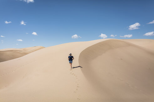 Hohe Winkel Ansicht der Frau zu Fuß auf Sand in Great Sand Dunes National Park während sonnigen Tag - CAVF57574