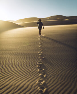 Rear view of carefree woman walking on sand at Great Sand Dunes National Park during sunset - CAVF57576