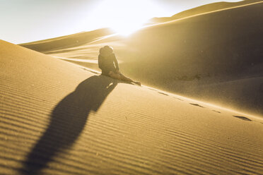 Frau sitzt bei Sonnenuntergang auf einer Sanddüne im Nationalpark - CAVF57577