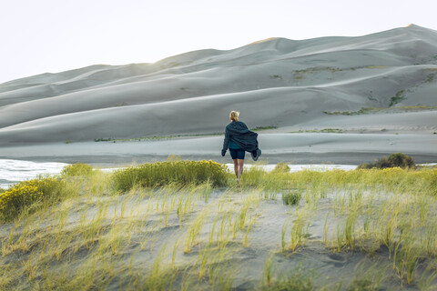 Rückansicht einer Frau inmitten von Pflanzen im Great Sand Dunes National Park, lizenzfreies Stockfoto
