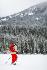 Frau mit Rucksack beim Wandern in einer verschneiten Landschaft - CAVF57583