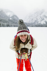 Smiling woman hiking on snow covered field - CAVF57584