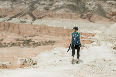 Rückansicht einer Wanderin mit Rucksack in der Wüste, lizenzfreies Stockfoto