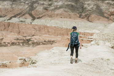 Rear view of female hiker with backpack walking at desert - CAVF57589