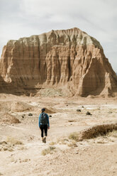 Rear view of female hiker with backpack exploring desert against rock formations during sunny day - CAVF57590