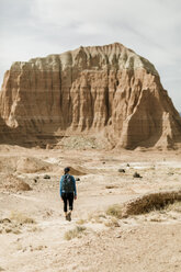 Rückansicht einer Wanderin mit Rucksack, die an einem sonnigen Tag die Wüste vor Felsformationen erkundet - CAVF57590