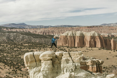 Weibliche Wanderin springt in voller Länge auf eine Felsformation in der Wüste - CAVF57597