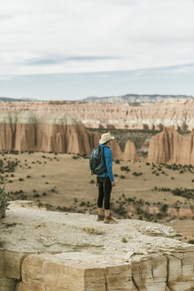 Wanderin mit Rucksack in voller Länge, die auf einer Felsformation stehend die Aussicht betrachtet - CAVF57598