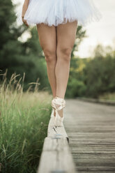 Niedriger Ausschnitt einer Balletttänzerin, die auf Zehenspitzen auf einer Stützmauer geht - CAVF57620