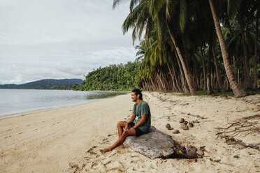 Man looking at view while sitting on wood - CAVF57654