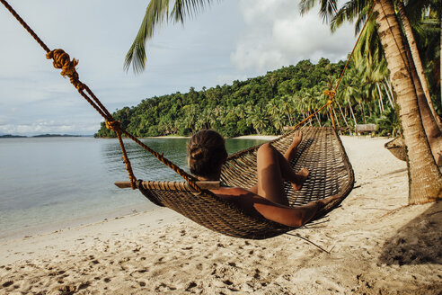 Young woman resting in hammock at beach - CAVF57666