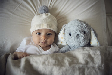 High angle view of baby boy with teddy bear lying on bed at home - CAVF57692