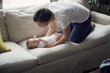 Hohe Winkelansicht der glücklichen Mutter, die ihren Sohn zu Hause auf dem Sofa ablegt - CAVF57697