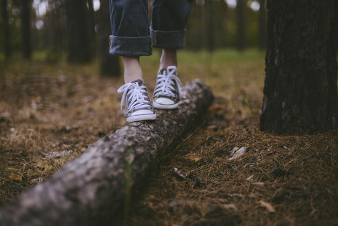 Tiefschnitt einer Frau, die auf einem Baumstamm im Wald geht - CAVF57709