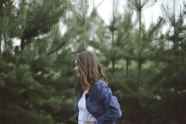 Side view of woman looking away while standing in forest - CAVF57710