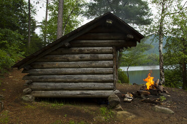 Campfire by log cabin in forest - CAVF57751