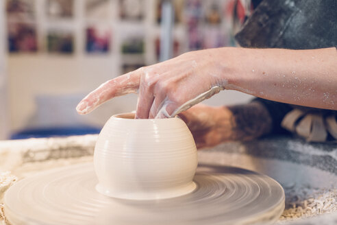 Midsection of woman making ceramics on pottery wheel at workshop - CAVF57761