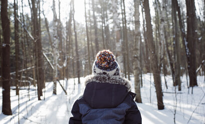 Rückansicht eines Jungen, der im Winter im Wald steht - CAVF57772