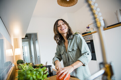 Lachende Frau beim Kürbisschneiden in ihrer Küche, lizenzfreies Stockfoto