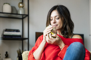 Mature woman relaxing at home, drinking lemon water - MOEF01725