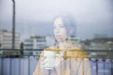 Traurige Frau, die am Fenster steht und Tee trinkt - MOEF01737