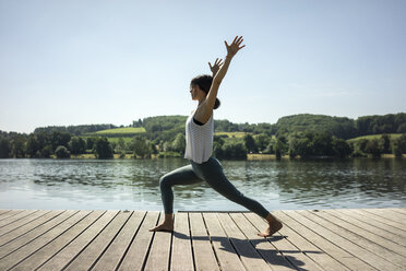 Ältere Frau übt Yoga im Sommer auf einem Steg an einem See - MOEF01761