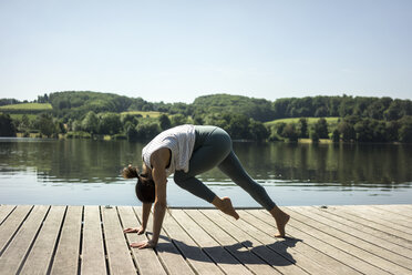 Ältere Frau übt Yoga im Sommer auf einem Steg an einem See - MOEF01762