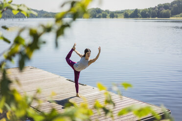 Ältere Frau übt Yoga im Sommer auf einem Steg an einem See - MOEF01763