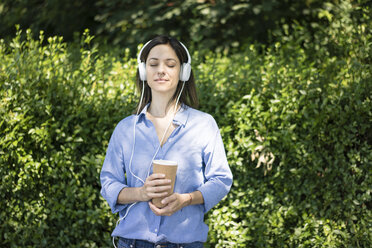 Frau mit Kopfhörern hört Musik in der Natur - MOEF01768