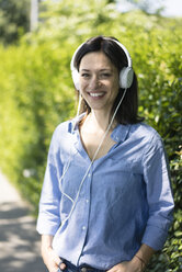 Frau mit Kopfhörern hört Musik in der Natur - MOEF01769