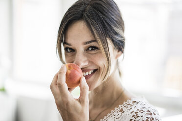 Laughing woman smelling an apricot - MOEF01791