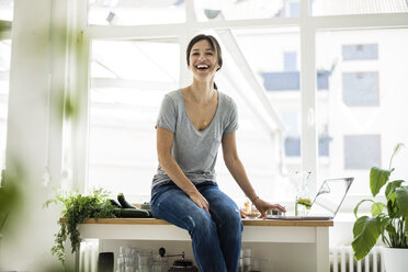 Woman sitting on kitchen table, searching for healthy recipes, using laptop - MOEF01806