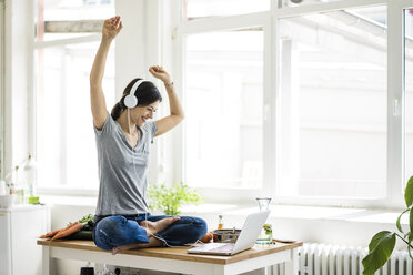 Woman sitting on kitchen table, searching for healthy recipes, using laptop - MOEF01816