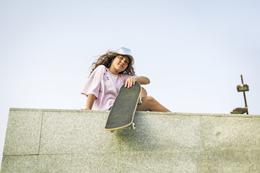 Girl with skateboard sitting on wall - ERRF00223