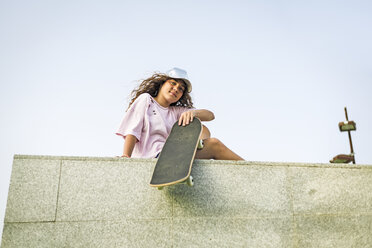 Mädchen mit Skateboard an der Wand sitzend - ERRF00223