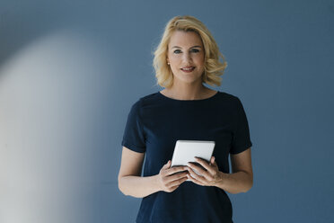 Portrait of smiling blond woman holding tablet - KNSF05388