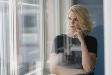 Serious blond woman looking out of window - KNSF05390