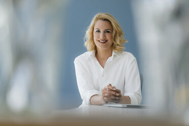 Portrait of smiling businesswoman sitting at table - KNSF05392