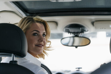 Lächelnde Geschäftsfrau im Auto, die sich umdreht - KNSF05400