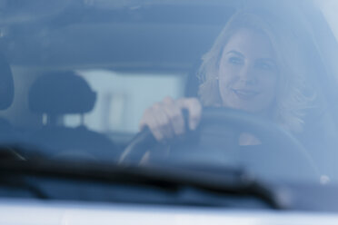 Lächelnde Frau am Steuer eines Autos - KNSF05415