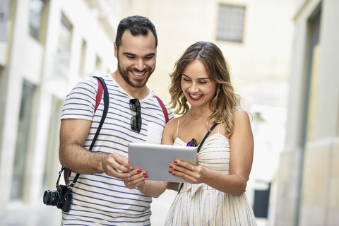 Spanien, Andalusien, Malaga, glückliches Touristenpaar in der Stadt mit Blick auf die Tafel, lizenzfreies Stockfoto