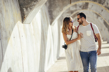Spanien, Andalusien, Malaga, glückliches Touristenpaar beim Spaziergang unter einem Torbogen in der Stadt - JSMF00620