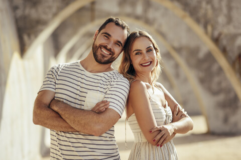 Spanien, Andalusien, Malaga, Porträt eines glücklichen Touristenpaares unter einem Torbogen in der Stadt, lizenzfreies Stockfoto