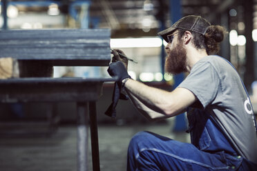Seriöser männlicher Arbeiter bei der Arbeit an Blechen in einer Stahlfabrik - CAVF57836