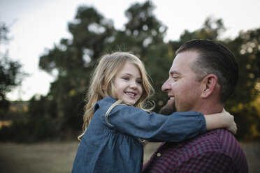 Cheerful father and daughter playing on field - CAVF57852