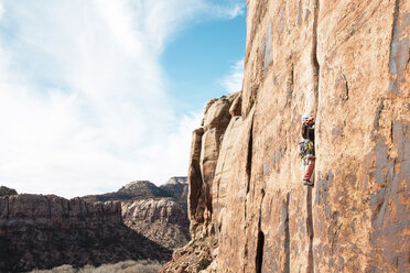 Side view of female hiker climbing mountain against cloudy sky - CAVF57858