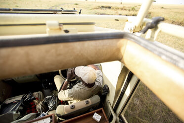 Blick von oben auf einen Mann, der in einem Geländewagen im Serengeti-Nationalpark sitzt - CAVF57877