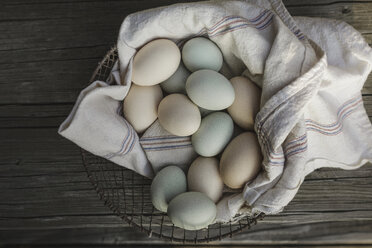 Draufsicht auf Eier auf Stoff in einem Korb auf einem Holztisch - CAVF57919